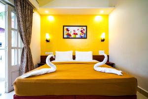 a bedroom with a bed with swans on it at Grande Ave Maria Resort in Candolim