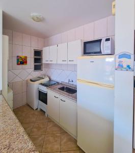 una pequeña cocina con nevera y microondas en Lexus Residence Apto 304, en Florianópolis