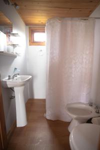 a bathroom with a sink and a toilet and a shower curtain at Centro Los Alamos in Maldonado