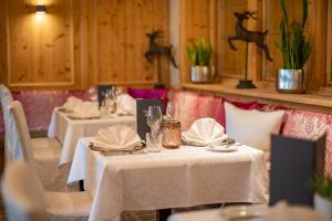 a restaurant with two tables with white tablecloths and napkins at Superior Sport und Familienresort Alpenblick in Zell am See