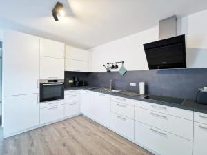 a kitchen with white cabinets and a flat screen tv at Rehkitz in Baiersbronn