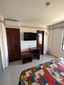 een slaapkamer met een bed, een bureau en een televisie bij Hotel el Mayo Inn in Culiacán