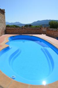 una gran piscina azul con una pared de ladrillo en EL CONVENTO Vivienda Rural Jaén Andalucía España en Carchelejo