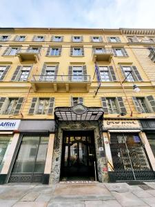 un grand bâtiment jaune avec une porte à l'avant dans l'établissement Green Class Hotel Astoria, à Turin