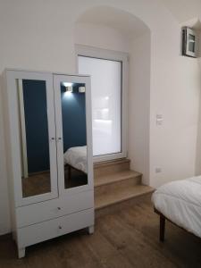 ein Schlafzimmer mit einer Kommode mit einem Spiegel und einer Treppe in der Unterkunft la Dimora di Rina in Trani