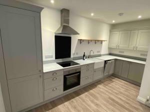 a kitchen with white cabinets and a sink and a stove at Argyle House - Stunning 2 Bed Cottage In Eyemouth in Eyemouth