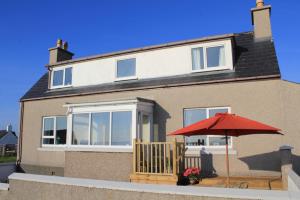 a house with a red umbrella in front of it at Seascape Cottage in Knock
