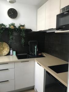 eine Küche mit Spüle und einer Uhr an der Wand in der Unterkunft L'appart 45 in Rodez