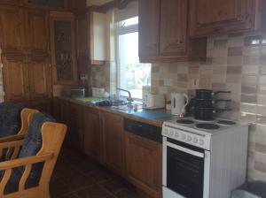 a kitchen with wooden cabinets and a stove top oven at Rossport bungalow with an Atlantic view in Ballina