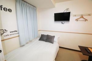 sypialnia z łóżkiem i telewizorem na ścianie w obiekcie Hotel Yuyukan - Vacation STAY 10008v w Tokio