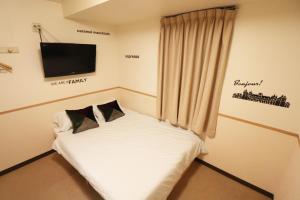 Cette chambre comprend un petit lit et une télévision murale. dans l'établissement Hotel Yuyukan - Vacation STAY 10008v, à Tokyo