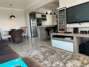 uma sala de estar com uma televisão grande e uma cozinha em Sunset em Ponta Grossa