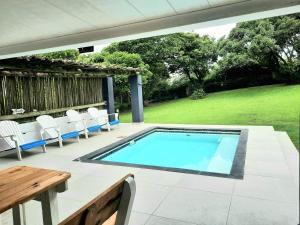 a swimming pool on a patio with chairs and a table at Anchors Rest in Port Shepstone
