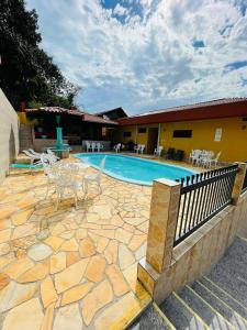 a patio with a pool and chairs and a building at Residencial Vista Bela in Bombinhas
