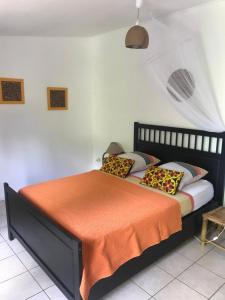 ein Bett mit einer orangefarbenen Decke und Kissen darauf in der Unterkunft Les Manguiers in Deshaies