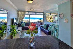 a vase with flowers on a table in a living room at Sands Beach Breaks Beach Front Ballito in Ballito