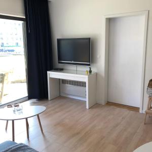 a living room with a flat screen tv on a white stand at Residentie Noordhinder in De Panne
