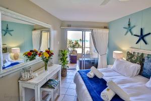 a bedroom with a bed and a desk and a mirror at Sands Beach Breaks Beach Front Ballito in Ballito