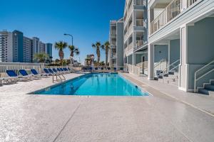 a swimming pool with blue chairs and a building at Grand Caribbean #103 in Orange Beach
