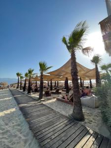 a beach with palm trees and people laying on the sand at Artemis Hotel Apartments in Keramoti