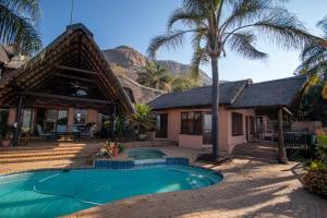 a house with a swimming pool and palm trees at Marina Views Guesthouse in Hartbeespoort