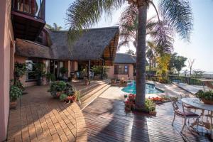 a house with a patio with a pool and palm trees at Marina Views Guesthouse in Hartbeespoort