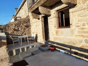 un edificio in pietra con tavolo e sedie su un patio di Casita de norma a Camariñas