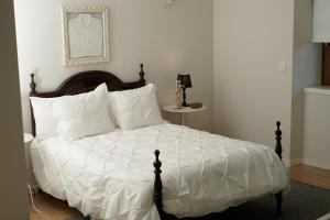 a bed with white sheets and pillows in a bedroom at Casa Centenária Povoa Nova in Seia