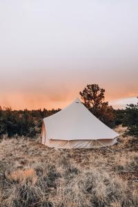 a tent in a field with a sunset in the background at Wander Camp Grand Canyon in Valle