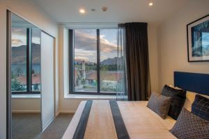 a bedroom with a bed and a large window at Ramada Queenstown Central in Queenstown