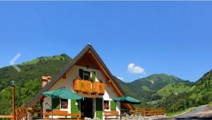 una casa con montagne verdi sullo sfondo di Rifugio Fornas a Tolmezzo