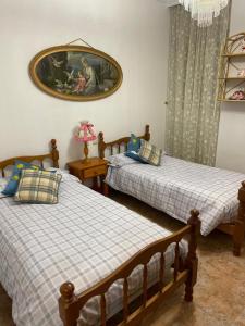 een slaapkamer met twee bedden en een schilderij aan de muur bij Casa Luisa in Granada
