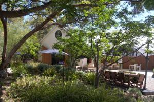 a garden with benches and trees in front of a building at The Farm Willunga in Willunga