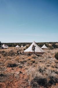 a man standing in front of a tent in a field at Wander Camp Grand Canyon in Valle