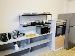 a kitchen with a microwave and a refrigerator at Charmant appartement de cœur de ville - 2 chambres lits Queen size - NETFLIX - WIFI in Cherbourg en Cotentin
