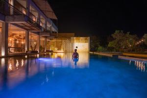 a person sitting in a swimming pool at night at Hotel Makaab&aacute; Eco-Boutique in Bacalar