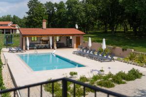 a swimming pool with chairs and a house at Vitis Apartment Istra in Tinjan