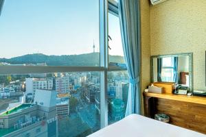 una camera da letto con una grande finestra con vista sulla città di Myeongdong Merlin Hotel a Seul