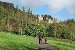 a man walking a dog on a path with a castle at Loughview chalet in Whitehouse Lower
