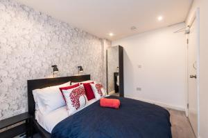 a bedroom with a bed with red and white pillows at The Blossoms Studio Apartments in Liverpool