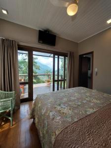 a bedroom with a bed and a sliding glass door at Casa no Céu in Petrópolis