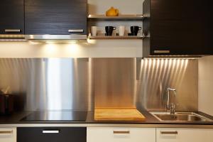 una cocina con fregadero de acero inoxidable y armarios negros en La Résidence Arles Centre, en Arles