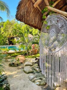 a garden with a pool and a straw umbrella at Zamunda Garden View in Tulum