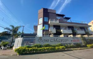 a hotel with a sign in front of a building at Don Marco's Hotel com Restaurante e Pizzaria in Guarujá