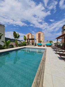 uma piscina com cadeiras e edifícios ao fundo em Don Marco's Hotel com Restaurante e Pizzaria no Guarujá