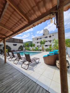 a patio with chairs and a swimming pool at Don Marco's Hotel com Restaurante e Pizzaria in Guarujá