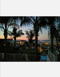 einen Blick auf den Sonnenuntergang über Palmen und eine Stadt in der Unterkunft Palm View Guest House in Pretoria