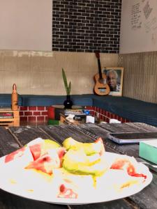 a plate of fruit on a table with a guitar at The Greenhouse Hostel Arusha Tanzania in Arusha
