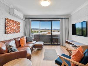a living room with a couch and a large window at Astrids at Central Park in Jindabyne