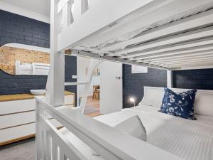 a bedroom with a loft bed and a kitchen at Astrids at Central Park in Jindabyne